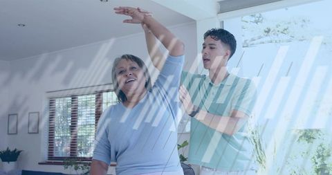 Caregiver guiding senior woman stretching arm at home for mobility and wellness routine