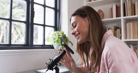 Professional female podcaster recording in home studio