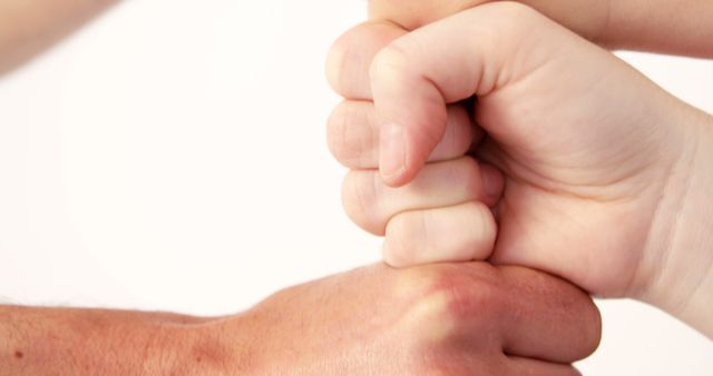 A Caucasian adult hand engages in a playful fist bump with a child's hand, with copy space. This gesture symbolizes trust and connection between generations.