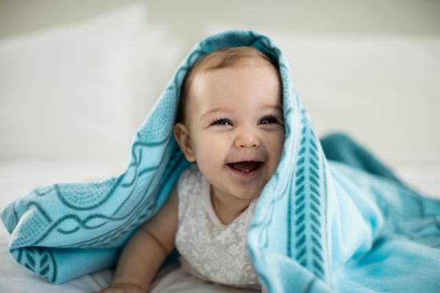 Cute baby girl under the blanket on bed - Download Free Stock Photos Pikwizard.com