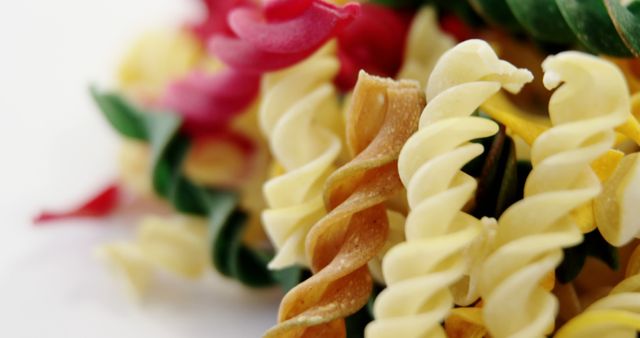 A close-up view of colorful fusilli pasta arranged artistically, with copy space. Its spiral shapes and vibrant hues make it visually appealing and suggest a focus on culinary presentation.