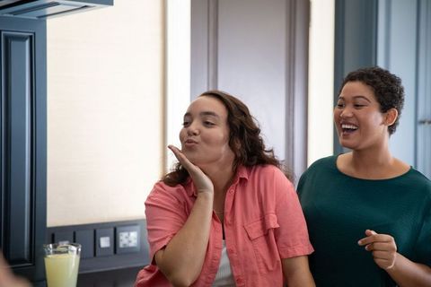 Playful Friends Blowing Kiss in Modern Kitchen