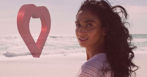 Woman relaxing by ocean with 3d heart marker and open space