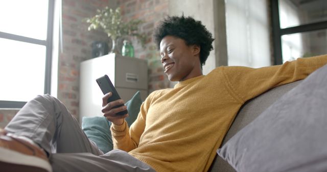 Smiling Person Relaxing on Sofa Using Smartphone at Home - Download Free Stock Images Pikwizard.com