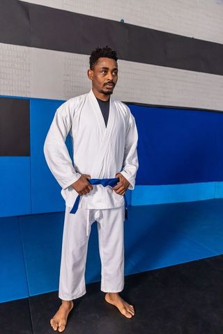 Focused Martial Artist Standing in Dojo with Blue Belt