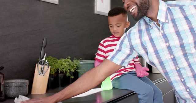 Smiling Father Cleaning Kitchen Counter with Son - Download Free Stock Images Pikwizard.com