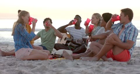 Young Adults Enjoying Music and Drinks at Beach Gathering