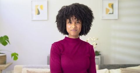 African American Woman Smiling on Sofa Wearing Maroon Turtleneck in Cozy Minimal Living Room
