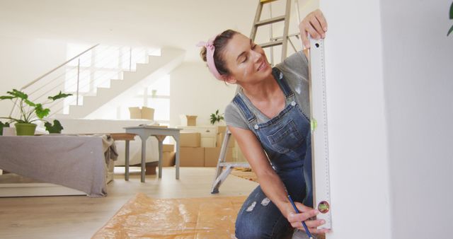 Happy caucasian woman measuring wall surface with level. Lifestyle, domestic life, house interior and work, unaltered.