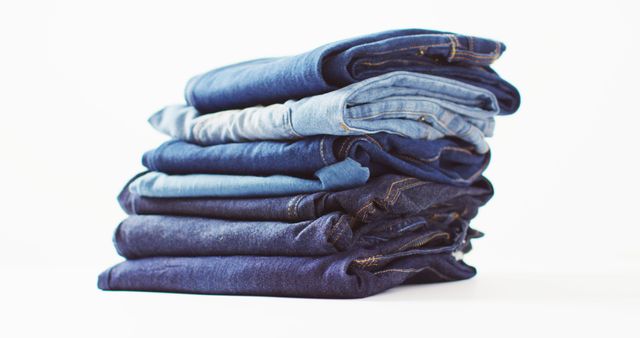 Close up of folded jeans with different shades on white background with copy space. Denim day, material, style and design concept.