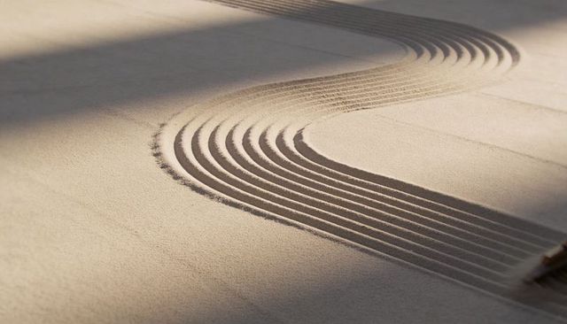 Zen garden sand raking into s-shaped curves for minimal meditative composition