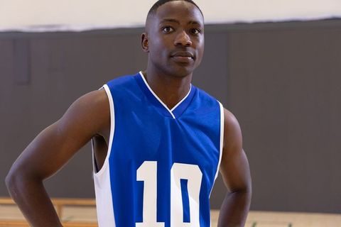 Focused male basketball player wearing blue jersey number 10 standing on indoor court