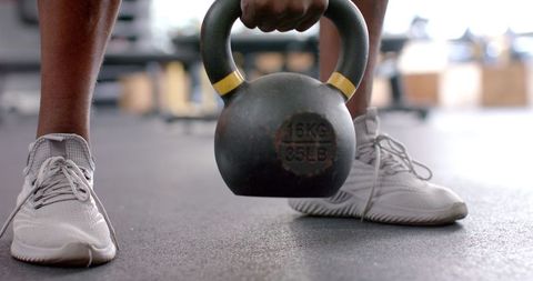Athletic individual lifting kettlebell for strength training at gym