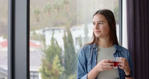 Peaceful Woman Enjoying Tea by Window in Modern Apartment