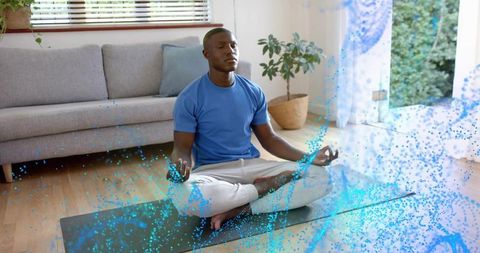 Meditating man practicing mindfulness on yoga mat at home surrounded by blue energy glow