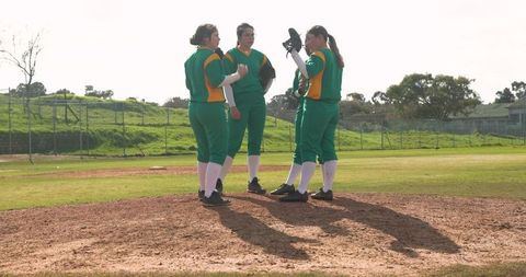 Female softball teammates strategizing on pitcher's mound