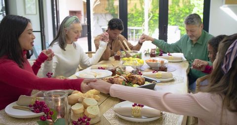 Multigenerational family holding hands around roast turkey dinner celebrating togetherness