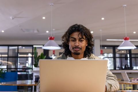 Remote worker concentrating on laptop in modern coworking space with pendant lights