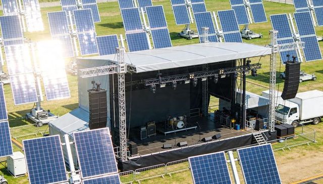 Outdoor concert stage at solar farm with flown pa arrays, drum kit and truss canopy