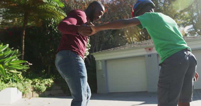 African american dad teaching his son to skateboard in the front yard. fatherhood and love concept