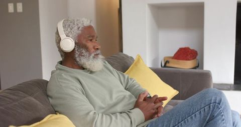 Senior man enjoying music on sofa with headphones