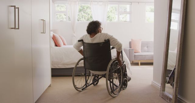Senior african american woman sitting in wheelchair in bedroom. Senior lifestyle, disability, free time and domestic life.