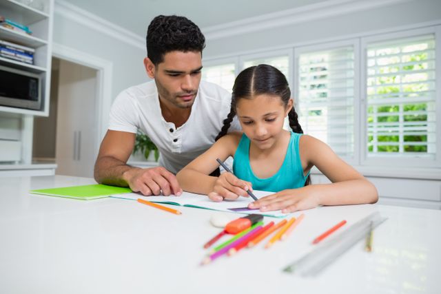 Father helping his daughter with her homework at home shows supportive parenting and strong family bonds. Useful for topics related to parenting advice, education tips, family activities, and home-based learning.