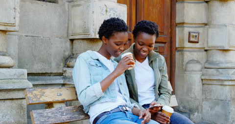 Smiling Twin Sisters Enjoying Time Together with Coffee in City