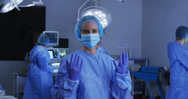 Portrait of caucasian female surgeon wearing face mask and protective clothing in operating theatre. medicine, health and healthcare services during covid 19 coronavirus pandemic.