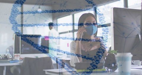 Asian woman wearing surgical mask using smartphone in open-plan lab with dna overlay