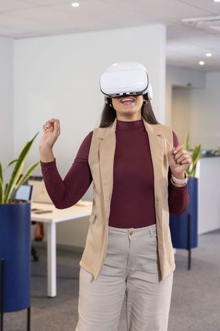 Midadult woman wearing vr headset exploring virtual workspace and immersive office tech
