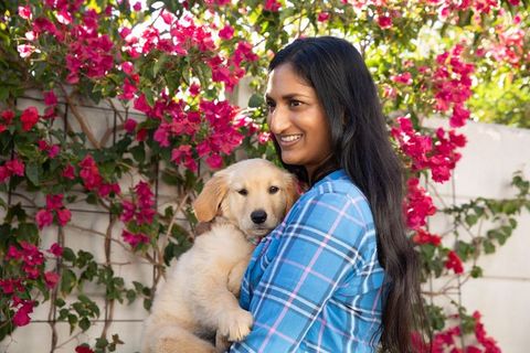 Woman embracing golden retriever puppy in blossoming garden