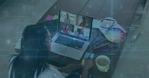 Woman joining remote video meeting while taking design notes with color wheel and coffee