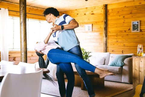 Joyful couple dancing in cozy rustic cabin interior