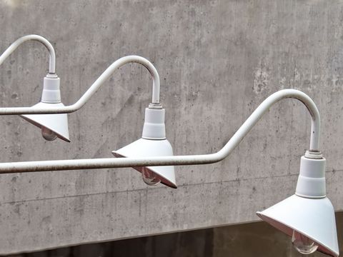 Three technology metal streetlights against concrete wall