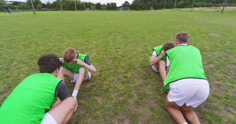 Teenagers Performing Partner Sit-ups on Grass Field in Team Training