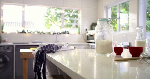 Sunlit kitchen island with flour jar and red measuring cups for home baking