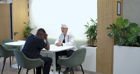 Black clinician and asian doctor discussing patient care in calm clinic lounge