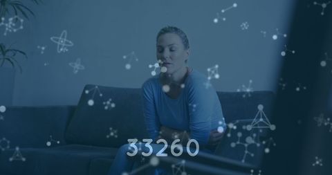 Digital health data overlay on pensive woman sitting on couch