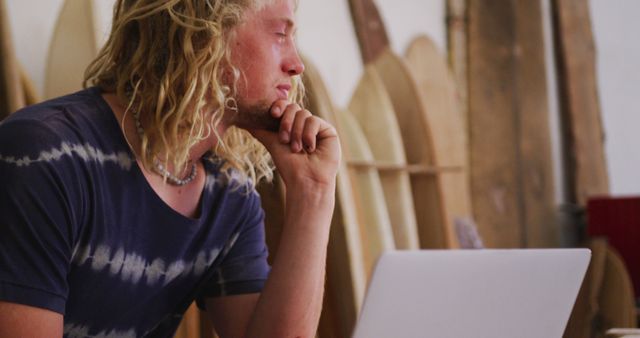 Man with Long Blonde Hair Working on Laptop in Surf Shop - Download Free Stock Images Pikwizard.com