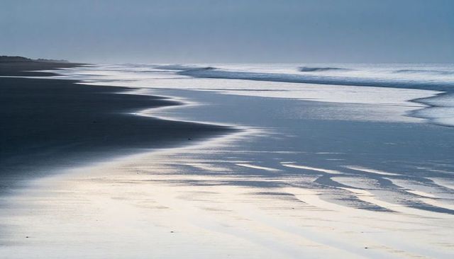 Empty coastal shoreline reflecting low tide ripples and sinuous tidal pools