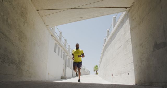 Man jogging through concrete underpass on bright sunny day - Download Free Stock Images Pikwizard.com