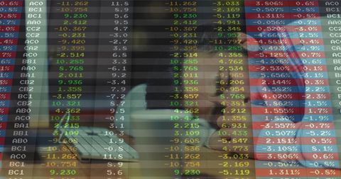 Man studying financial data on laptop with trading dashboard overlay, focused workspace