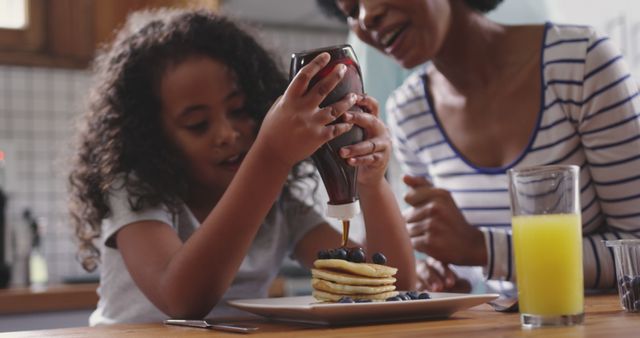 Mother and daughter enjoying breakfast with pancakes in kitchen - Download Free Stock Images Pikwizard.com