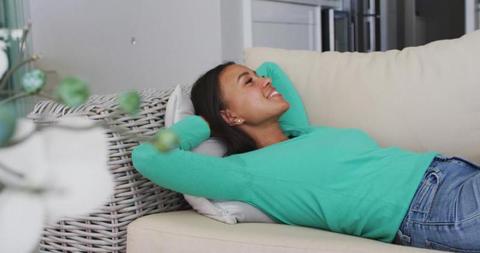 Woman Relaxing on Couch at Home with Arms Behind Head - Download Free Stock Images Pikwizard.com