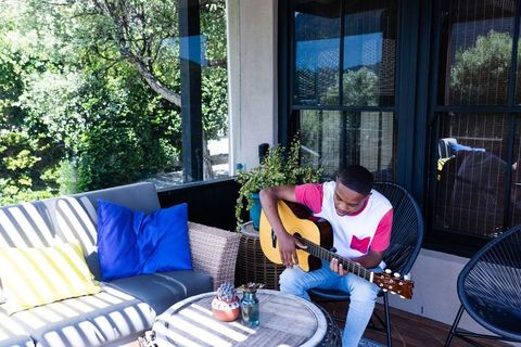 Teen Enjoying Sunny Day Playing Guitar Outside on Patio