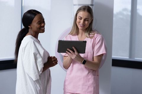 Female patient and radiology technologist reviewing diagnostic scans on tablet in clinic
