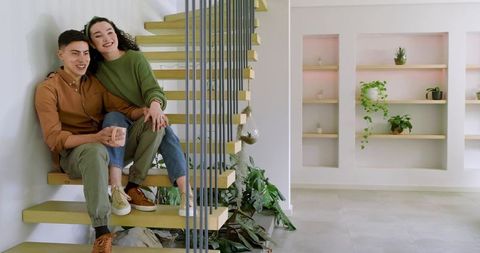 Couple relaxing on modern floating wooden staircase in minimalist interior