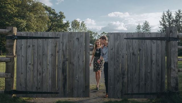 Romantic couple walking through rustic split-gate park holding hands