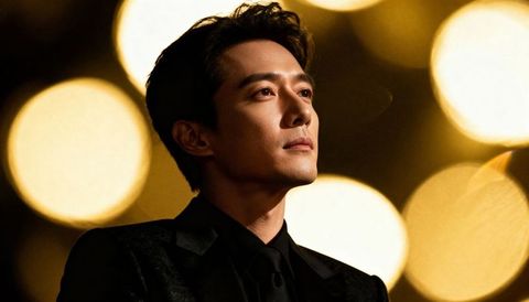 Confident asian man in black suit gazing upward with golden bokeh cinematic portrait